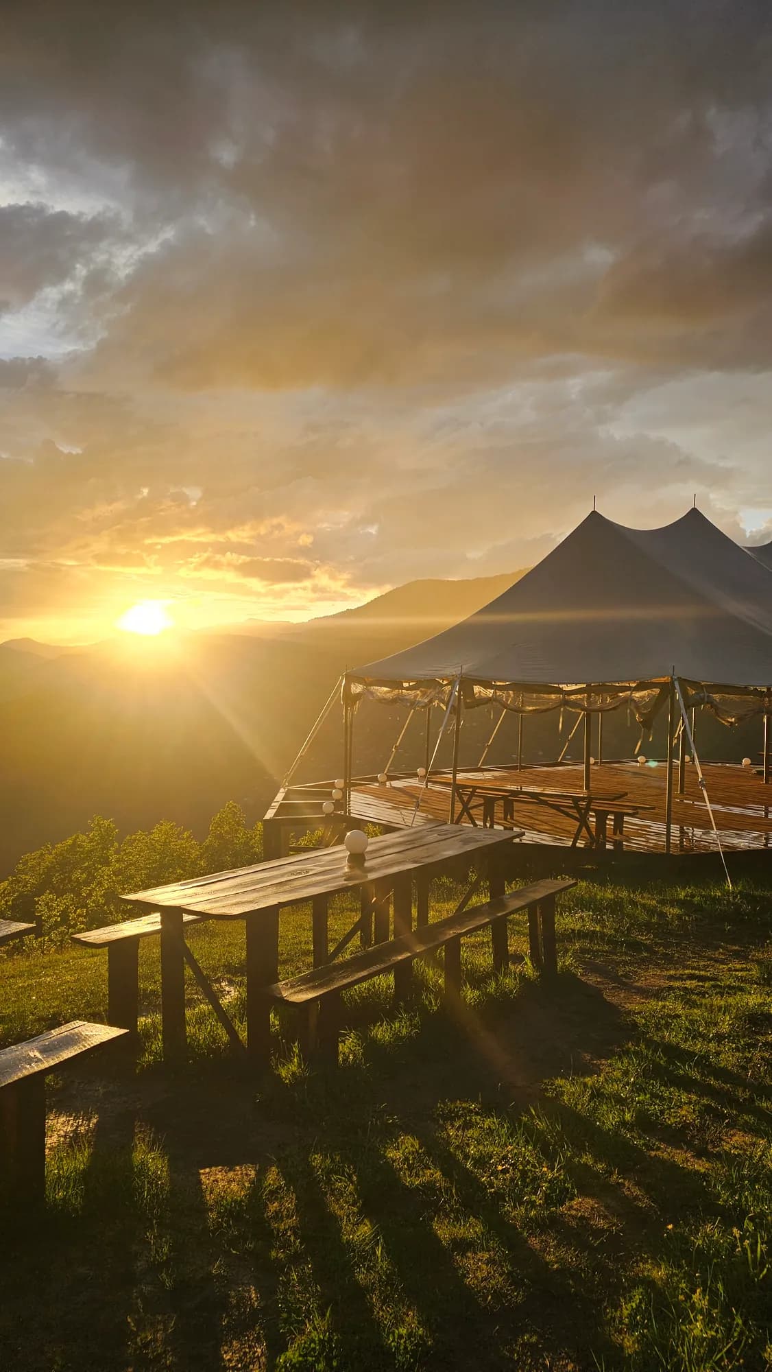 The sailcloth tent over the big platform at sunset, picnic tables in front