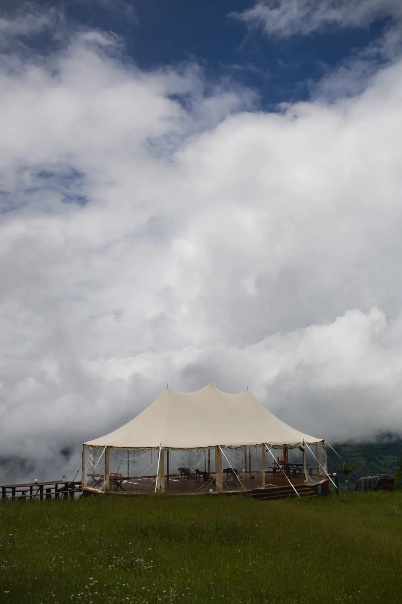The sailcloth tent on the hill with clouds over the mountains