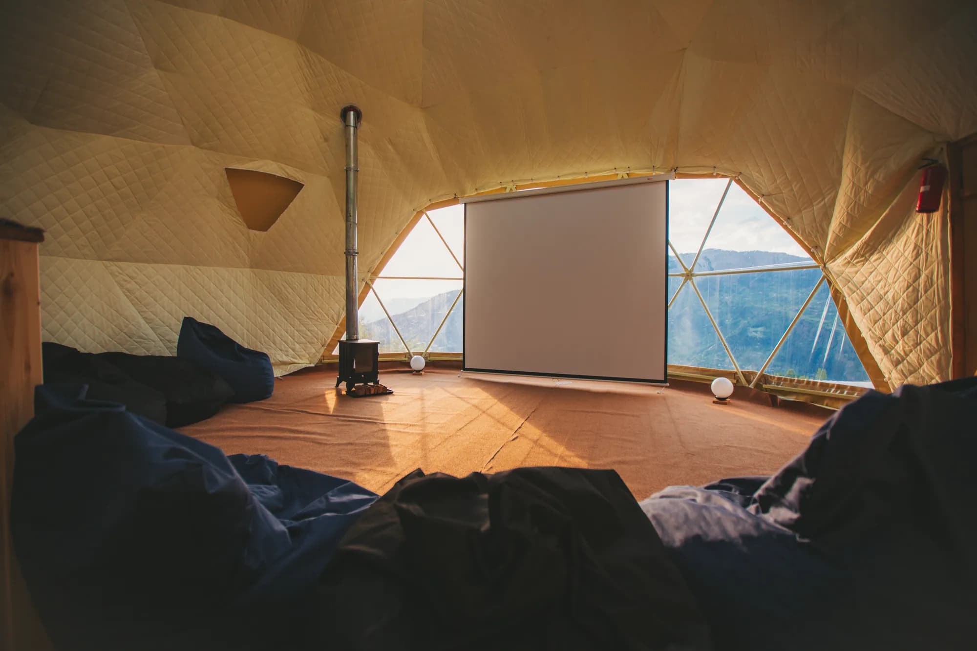Inside the yoga dome: wood stove, projector screen and windows onto the valley