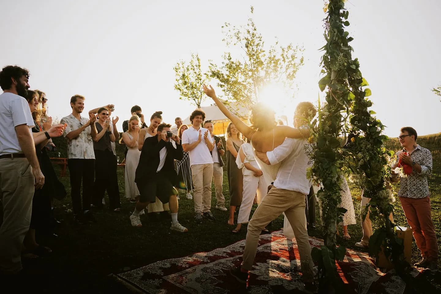 Guests cheering around the flower arch at sunset