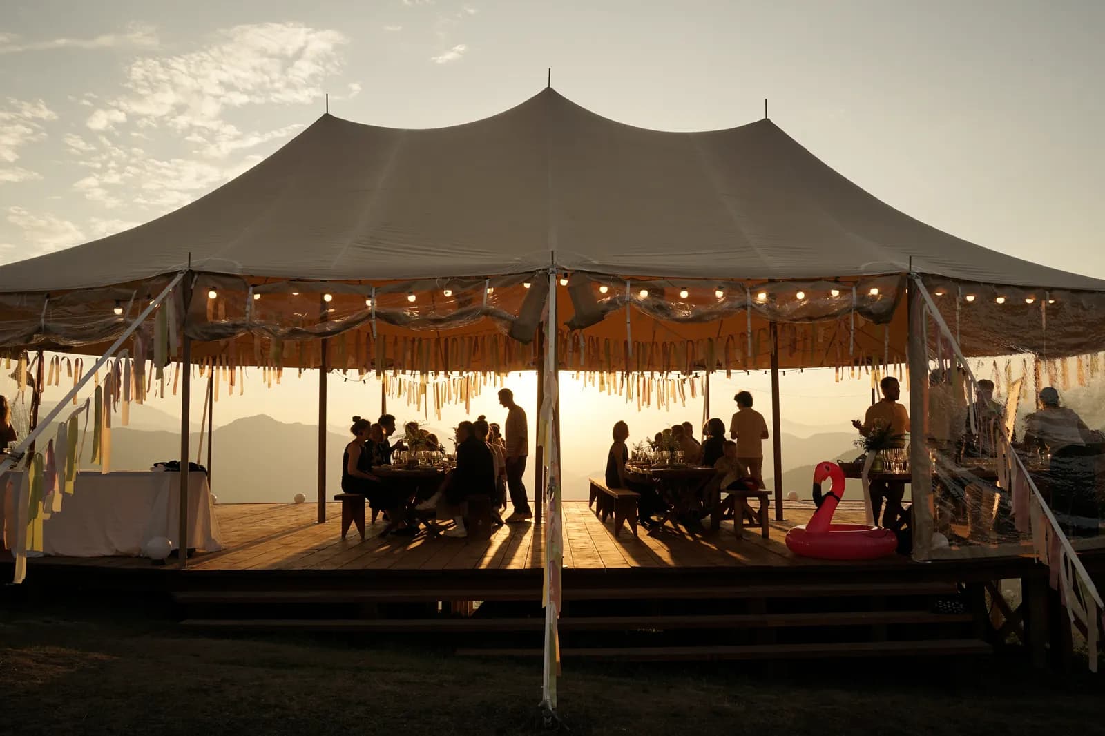 The wedding feast under the lit tent at dusk
