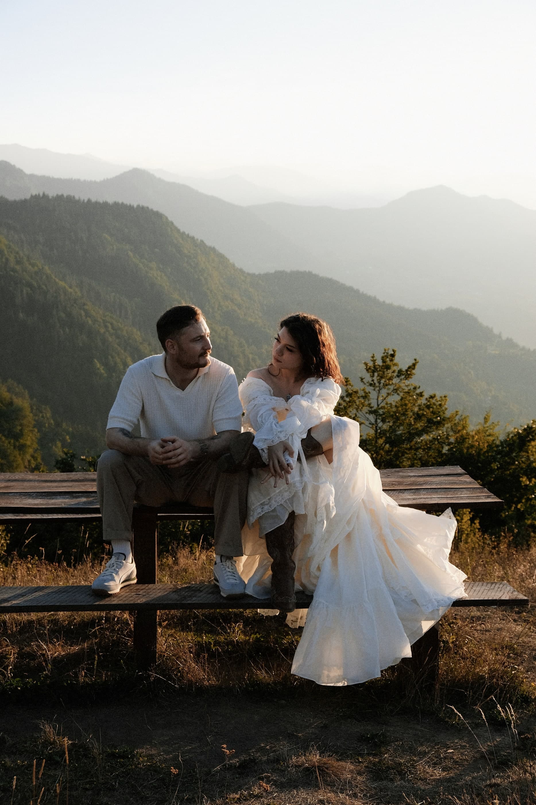 Couple in wedding attire on a bench with mountain views, Glamping Tago, Georgia.