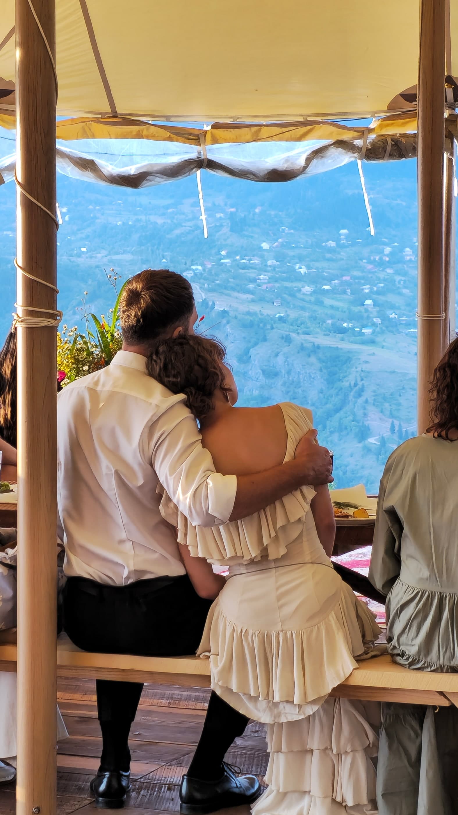 Couple embracing, looking at mountain village view from a tent, family wedding in Georgia, Glamping Tago, Georgia.